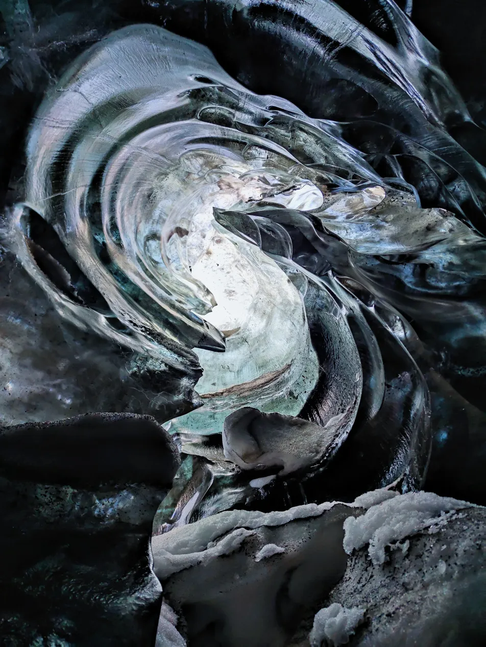 Interior de la cueva de hielo del Vatnajökull — espiral de hielo transparente y negro con luz filtrándose