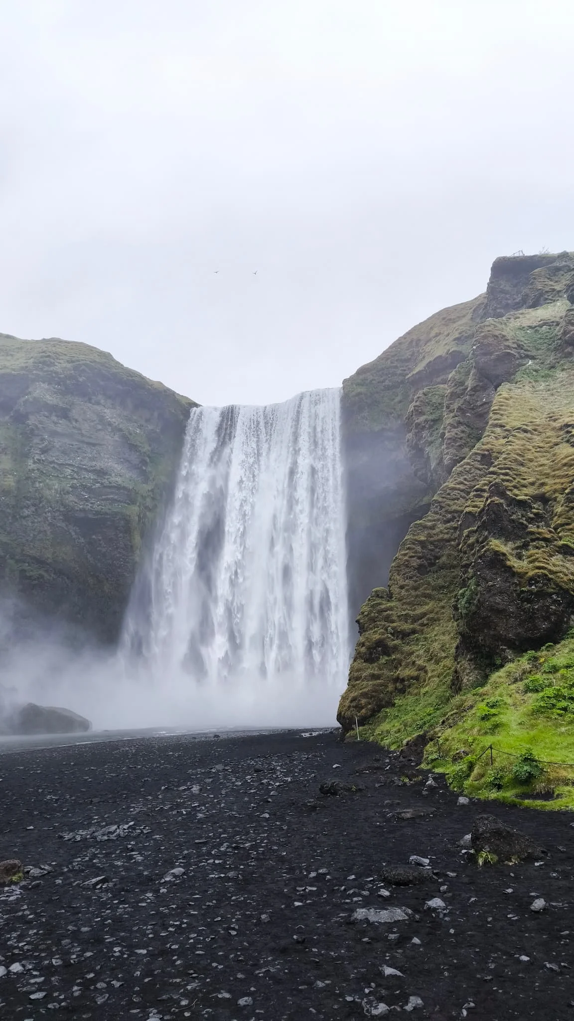 Skógafoss — cascada frontal enorme con niebla y acantilados verdes