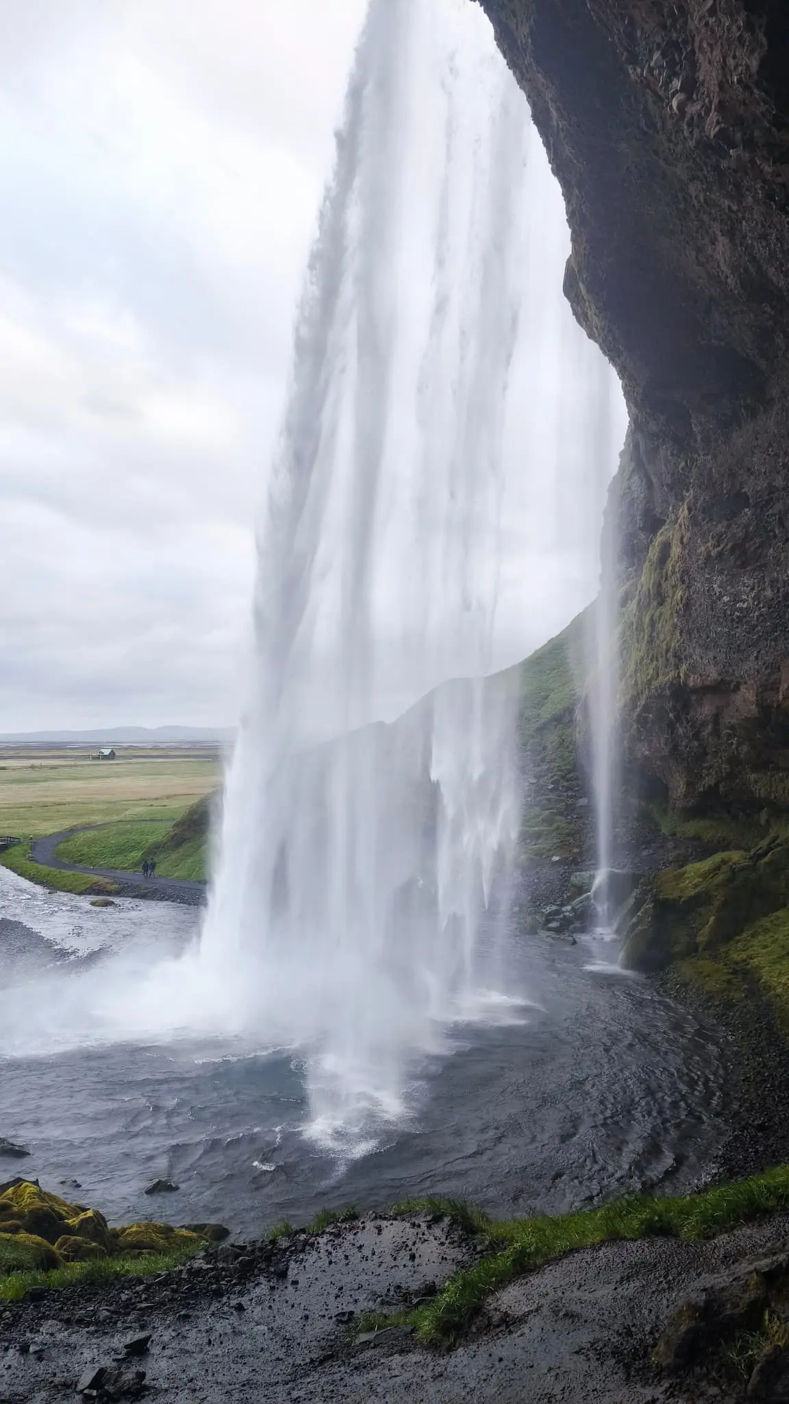 Vista desde detrás de Seljalandsfoss — el valle visto a través de la cortina de agua