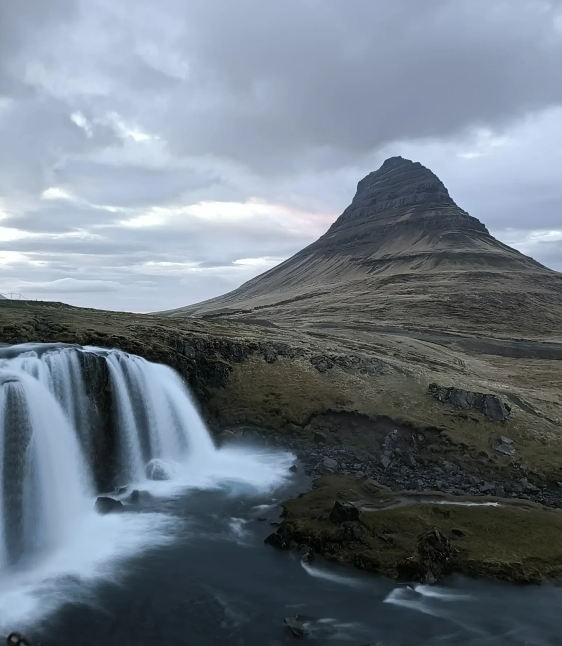 Kirkjufellsfoss con la montaña cónica Kirkjufell al fondo al atardecer