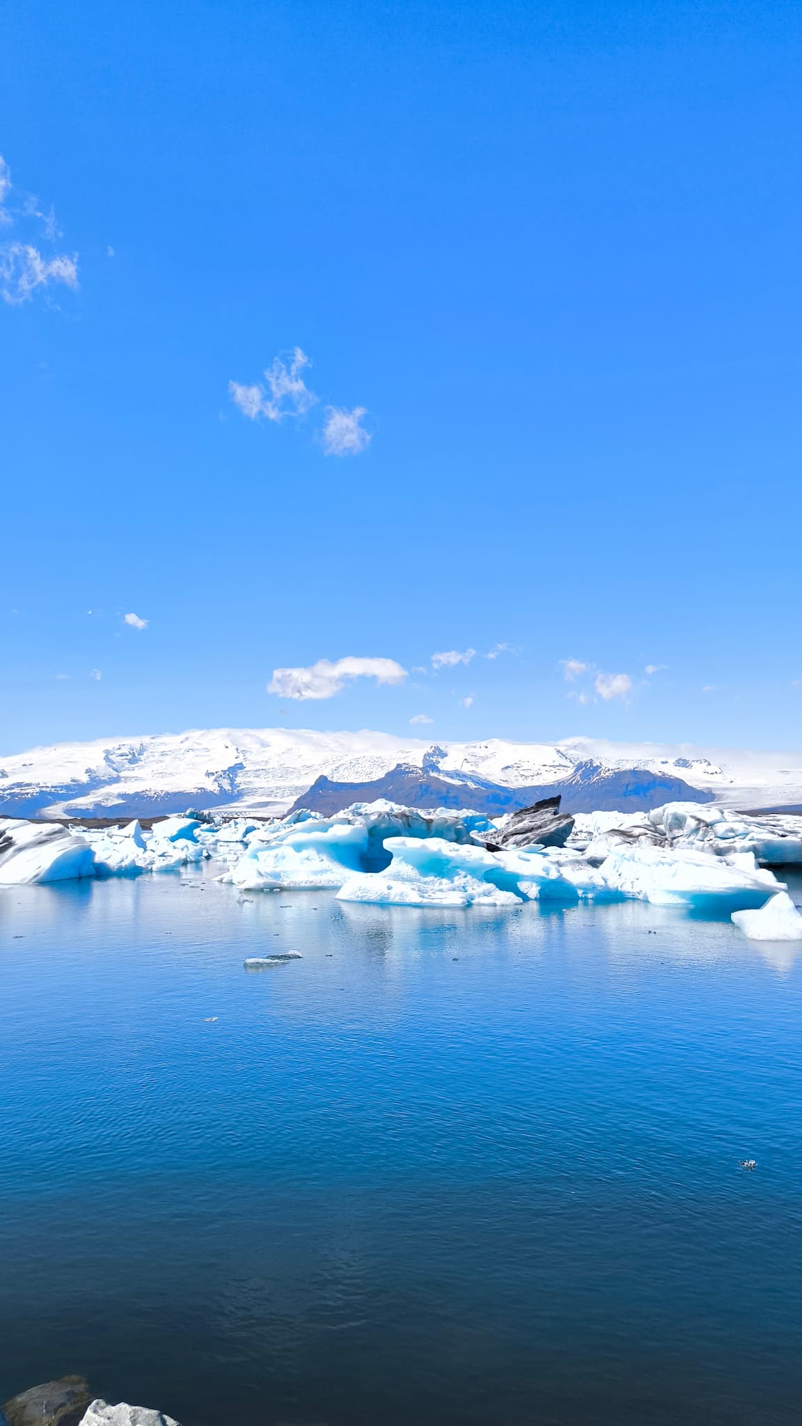 Laguna glaciar Jökulsárlón con icebergs bajo cielo azul y el glaciar Vatnajökull al fondo