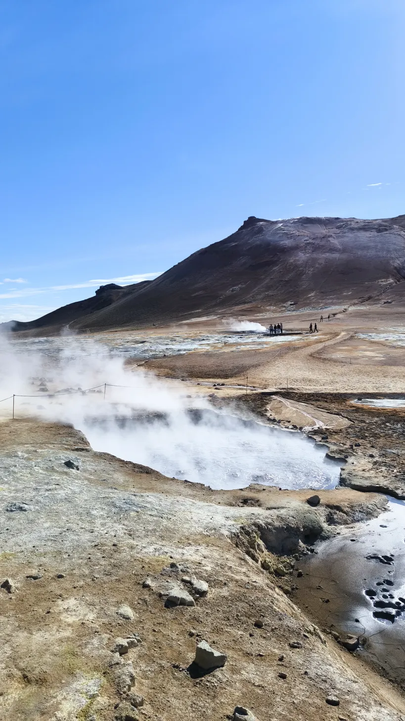 Fumarolas Hverir con vapor intenso y montaña volcánica al fondo cielo azul