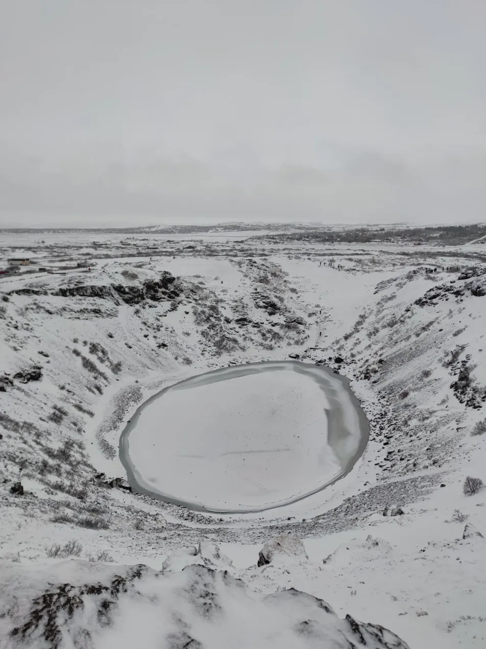 Cráter Kerid en invierno completamente nevado — el lago interior helado