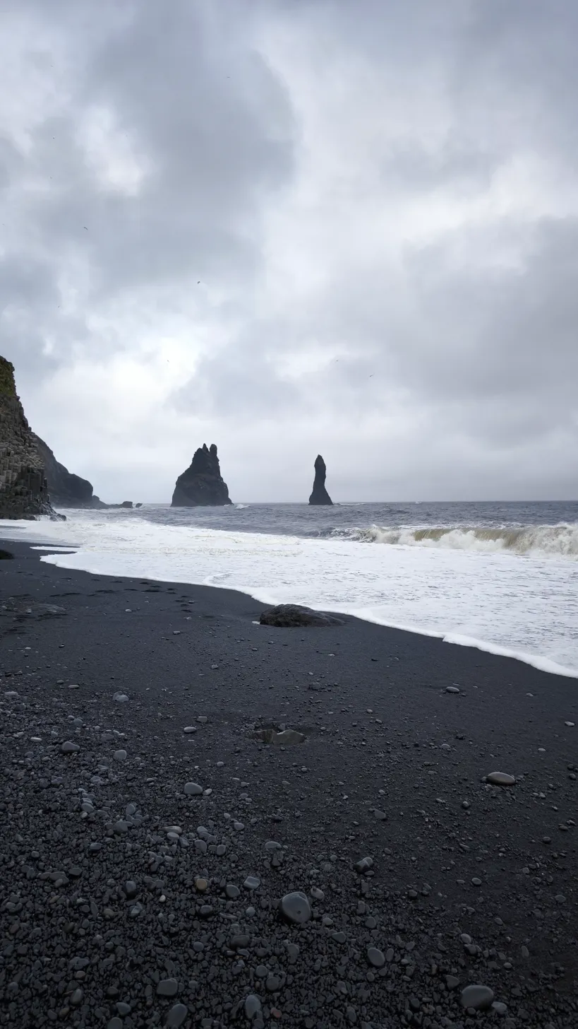 Playa negra Reynisfjara con los Reynisdrangar emergiendo del mar en invierno con oleaje fuerte